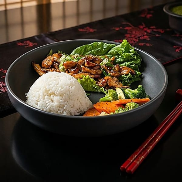 Teriyaki chicken, white rice, steamed vegetables, and lettuce in a dark bowl with chopsticks.